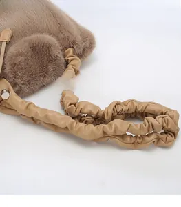 Detail of soft brown faux fur bag featuring a unique gathered pleated shoulder strap