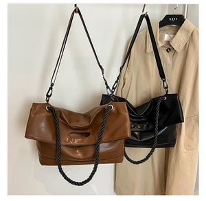 Close-up of vintage leather tote bag with braided handles and adjustable shoulder strap