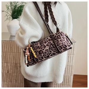 Detail of leopard print cylinder shoulder bag with beaded charm on model