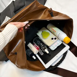 Detail view of large dark brown tote bag interior filled with tablet and cosmetics