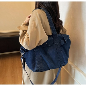 Detail of blue denim tote bag worn with trench coat in a minimalist home setting