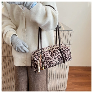 Detail of leopard print cylinder shoulder bag with beaded charm and dark brown handle