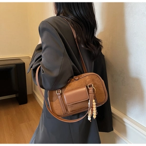 Detail view of a vintage brown suede Boston bag with a leather strap and wooden bead charm