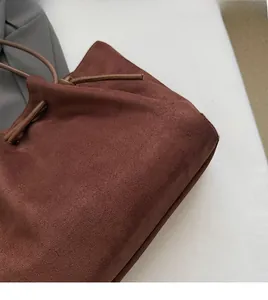 Detail of rust red suede tote bag showing soft pleated texture and drawstring feature