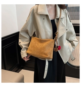 Close-up of brown suede hobo bag featuring retro charms and gold metal ring detail