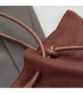 Detailed close-up of stitching and cord knot on a dark brown suede tote bag