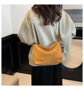 Detail of yellow hobo bag with tassel and pompom, worn by model in a vintage room
