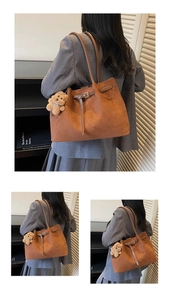 Detailed view of a brown suede tote bag with leather strap and plush bear charm