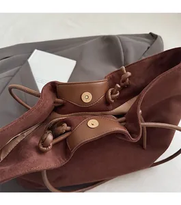 Detailed macro view of magnetic snap closure and suede texture on brown tote bag