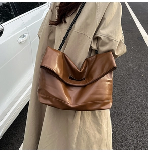 Brown leather tote with woven rope strap shown on a model in trench coat outdoors