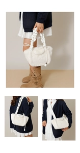 Detail of white fluffy plush handbag featuring a soft fur texture and leather bow accent