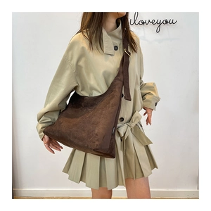 Dettaglio della borsa a secchiello in pelle scamosciata marrone con etichetta fashion
