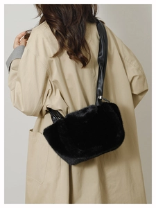 Detailed view of luxury black faux fur shoulder bag worn with a chic beige trench coat