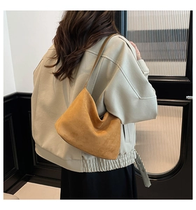 Close-up of ginger yellow suede hobo bag carried by model in casual minimalist setting