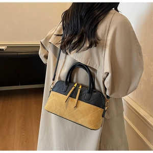 Detail of a chic quilted shell bag in black and yellow beige with adjustable shoulder strap