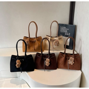 Detailed view of five colorful suede tote bags with cute bear charms on a white stand