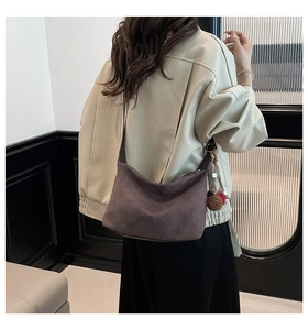 Detail of the suede crescent hobo bag in dark grey with decorative plush ball charm