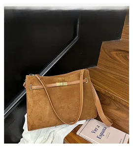 Detailed view of the vintage suede texture and golden metal buckle on the brown shoulder bag