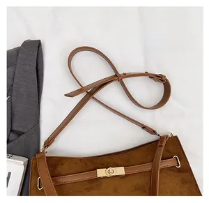 Detail view of brown suede shoulder bag with leather strap and gold metal twist lock