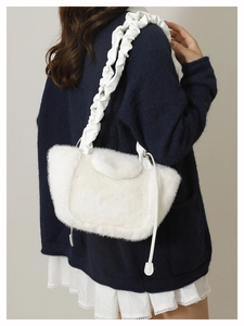 Detail of white plush shoulder bag featuring a soft faux fur texture and ruched cloud strap