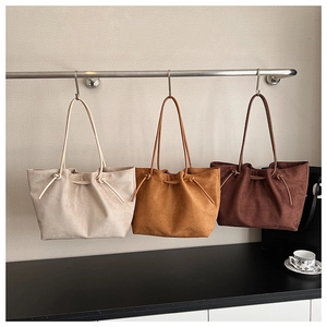 Suede tote bags in beige, camel, and dark brown hanging with knot details