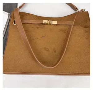 Detail of vintage brown suede crossbody bag featuring a gold metal twist lock closure