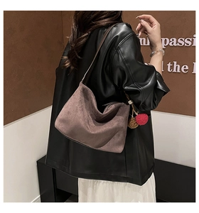 Detail of taupe faux suede tote bag with decorative pom-pom charms for autumn winter