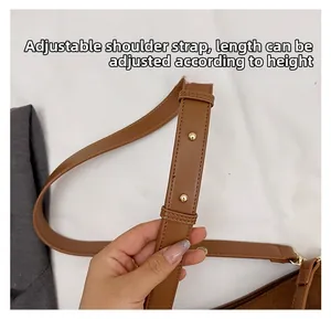 Detail of adjustable brown leather shoulder strap with gold buckle for crossbody bag