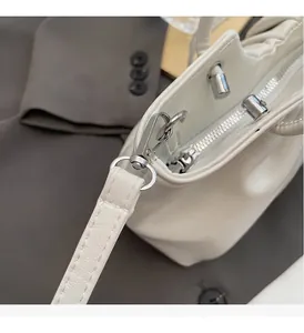 Macro di cerniera in metallo argento e dettagli su borsa a mano bianca in ecopelle