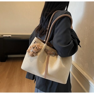 Detail der beigen Wildleder-Tote Bag mit braunem Lederbesatz und Plüschbär-Anhänger Zubehör