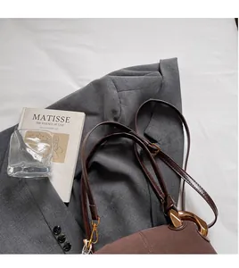 Detail of vintage brown suede crossbody bag with long leather strap and gold hardware