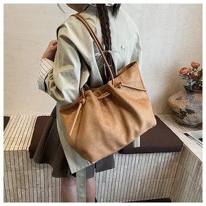 Detailed view of caramel suede tote bag with drawstring knot and slim shoulder straps