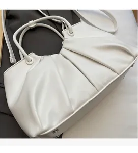 Dettaglio borsa a nuvola bianca plissettata con texture in similpelle e borchie sul fondo