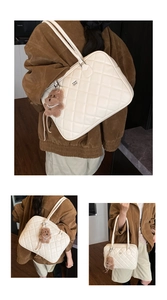 Detail of white quilted tote bag with diamond pattern, metal logo, and plush bear charm