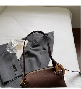 Detail of dark brown matte cylinder bag featuring metallic zippers and durable handle