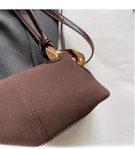 Close-up of brown suede fabric texture with gold metal buckle and fine stitching detail
