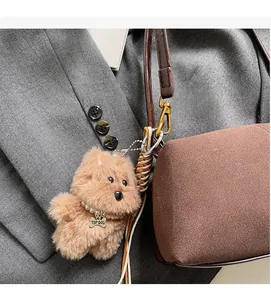 Macro detail of plush puppy bag charm with pearl necklace and gold metal bone tag