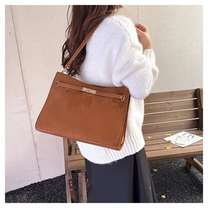 Detail of vintage brown suede shoulder bag with gold clasp shown on a model