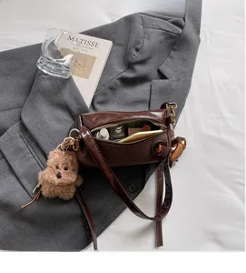 Detailed interior of deep brown barrel bag with plush dog charm and daily essentials