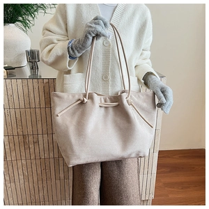 Detail of beige suede tote bag showing soft matte texture and decorative drawstring knot