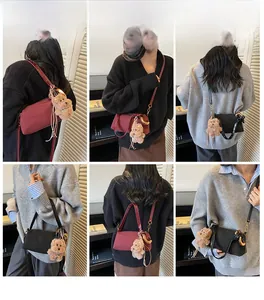 Detail view of burgundy and black crossbody bags with plush bear charm and gold hardware