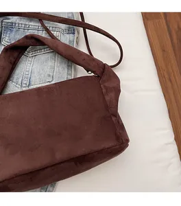 Detailed close-up of dark brown suede shoulder bag with soft texture and wide strap