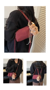 Detail of burgundy textured cylinder bag featuring a cute brown puppy plush keychain charm