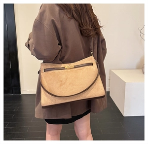 Detail of the golden metal lock on a vintage suede crossbody bag in khaki and brown