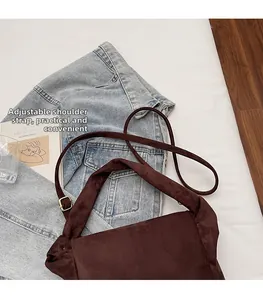 Detail of adjustable shoulder strap with gold metal buckle on dark brown nylon hobo bag