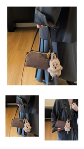 Detail of dark brown suede shoulder bag with long strap and plush bear charm pendant