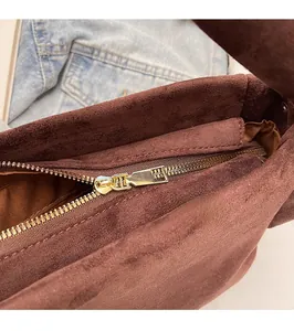 Detail of smooth gold zipper and high-quality dark brown suede texture on bag