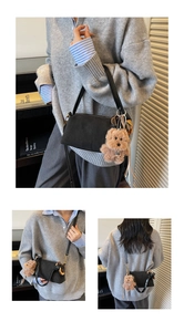 Detail of matte black cylinder bag with plush bear charm and golden hardware accents