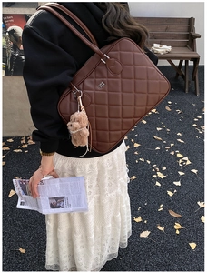 Brown quilted leather shoulder bag with plush bear charm for chic business commute