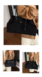 Close-up detail of black suede tote bag with leather straps and metallic buckle accents